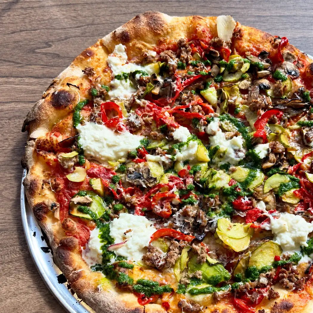 Grande pizza garnie de fromage frais, pesto, poivrons et courgettes chez Apollonia Pizza à Fès