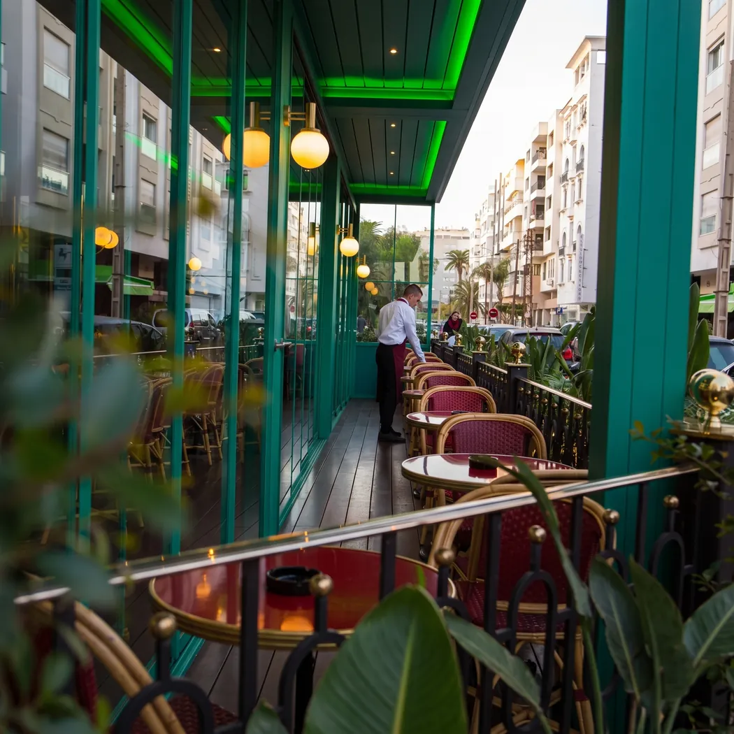Terrasse couverte du Vendôme, tables rondes et fauteuils rouges