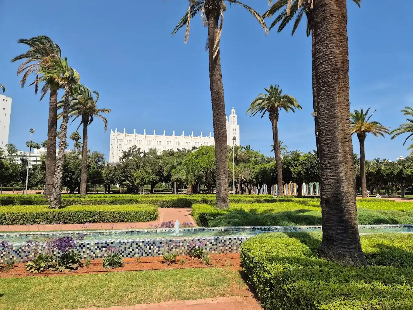 Massifs fleuris et bassin du parc de la Ligue arabe, bâtiment blanc au fond