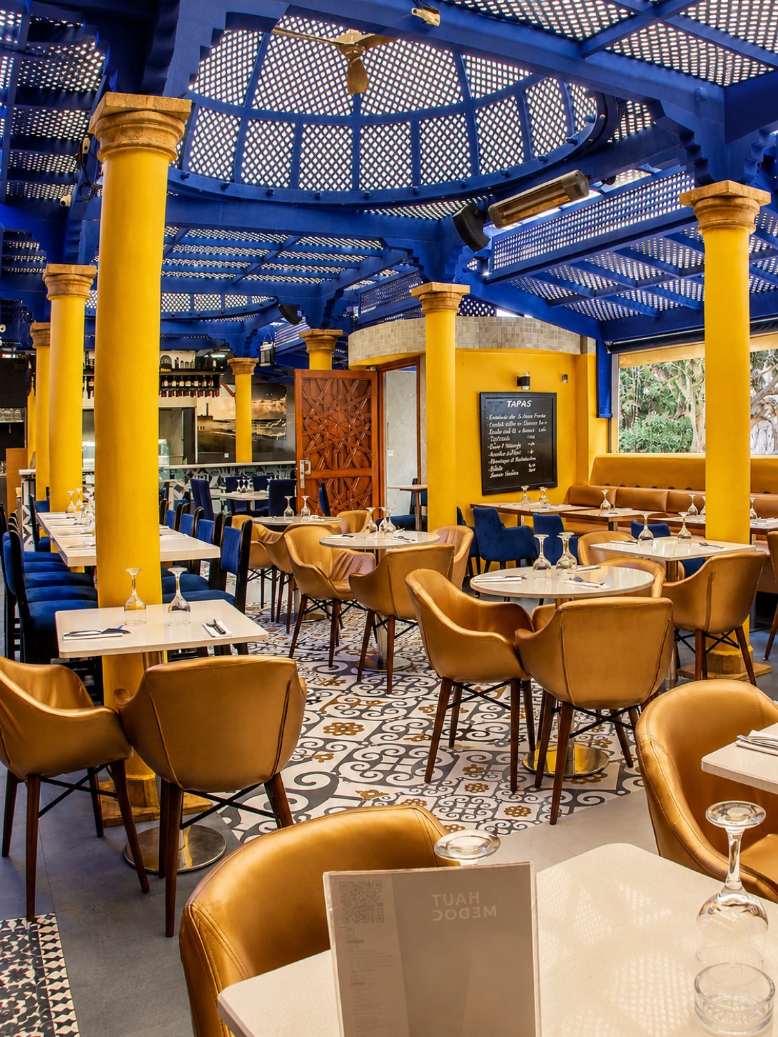 Salle des Deux Palais avec colonnes jaunes, verrière bleue et sol en carreaux de ciment
