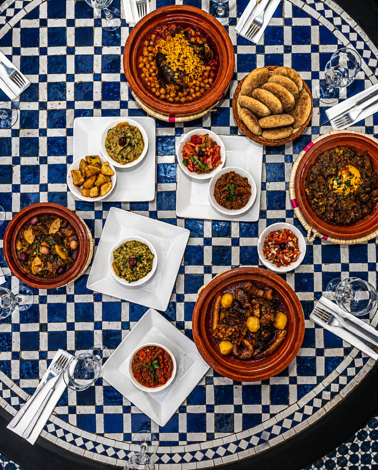 Vue du dessus aux Deux Palais à Rabat : tajines, salades marocaines et briouates sur une table en zellige bleu
