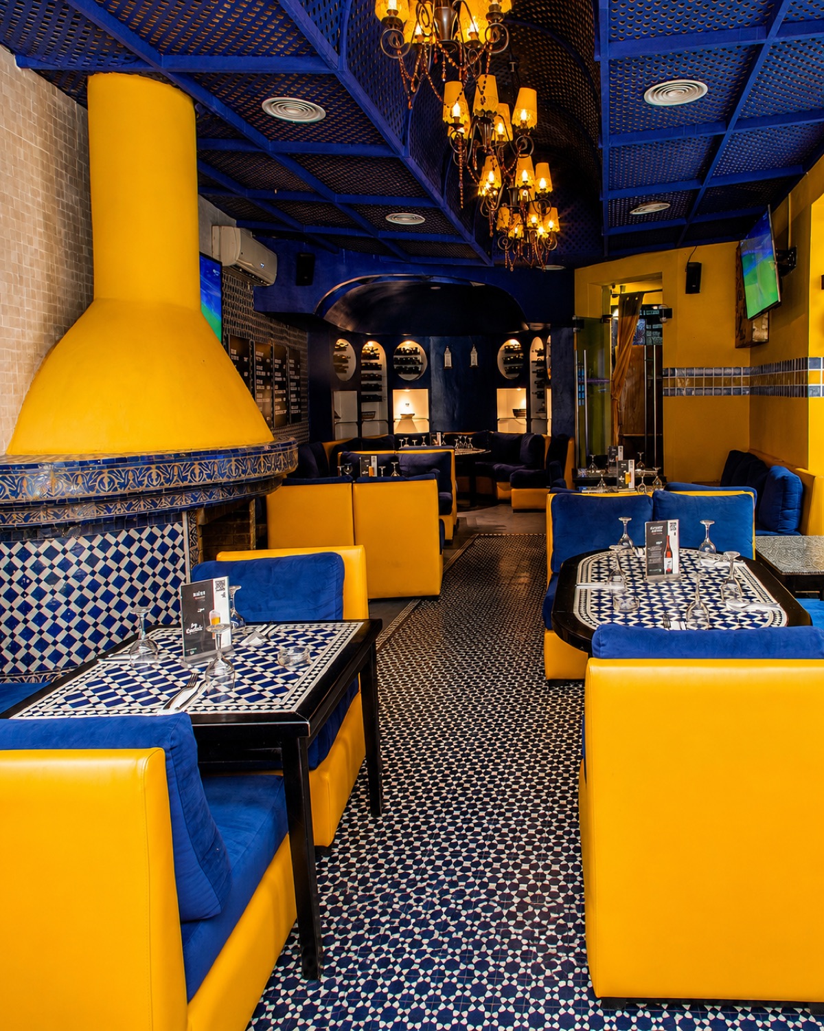 Banquettes jaunes et bleues, tables en zellige et hotte jaune aux Deux Palais