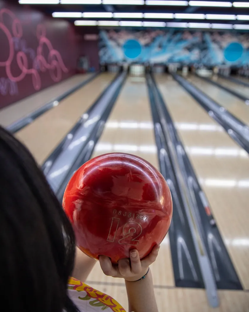 Boule rouge tenue face aux pistes éclairées de Tamaris Bowling