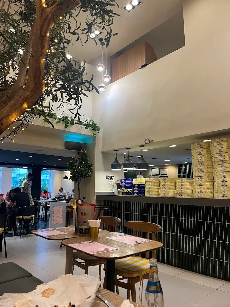 Little Mamma Agdal à Rabat : salle sous mezzanine, olivier et boîtes à pizza empilées au comptoir