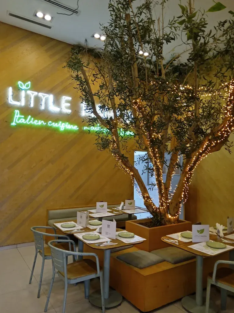 Little Mamma Agdal à Rabat : tables autour d'un olivier illuminé, néon « Little Mamma » au mur