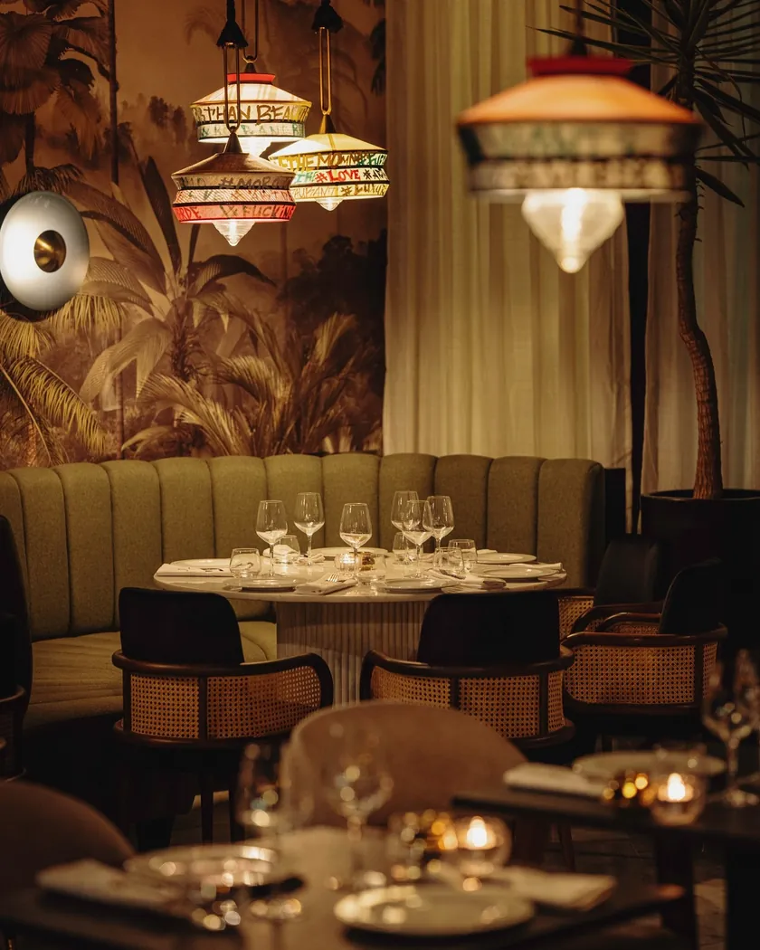 Salle de Verde Marrakech : banquette arrondie verte, papier peint tropical et suspensions en tissu