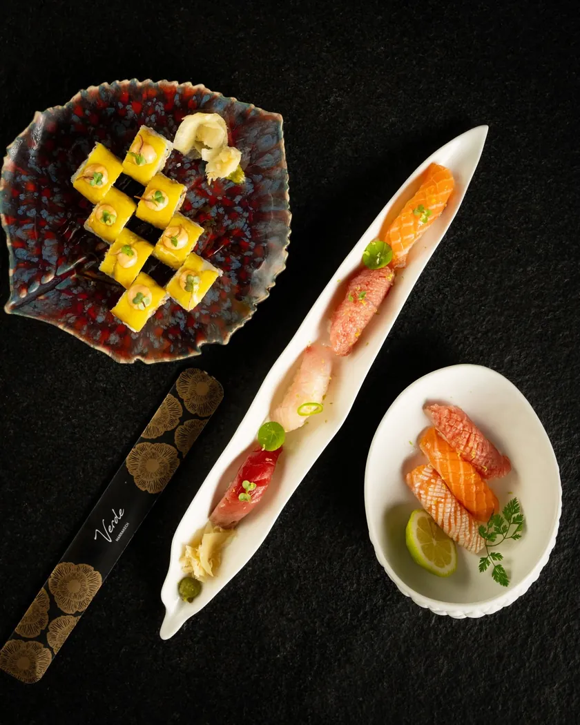 Makis dorés, nigiris et sashimis de saumon présentés sur fond noir chez Verde Marrakech