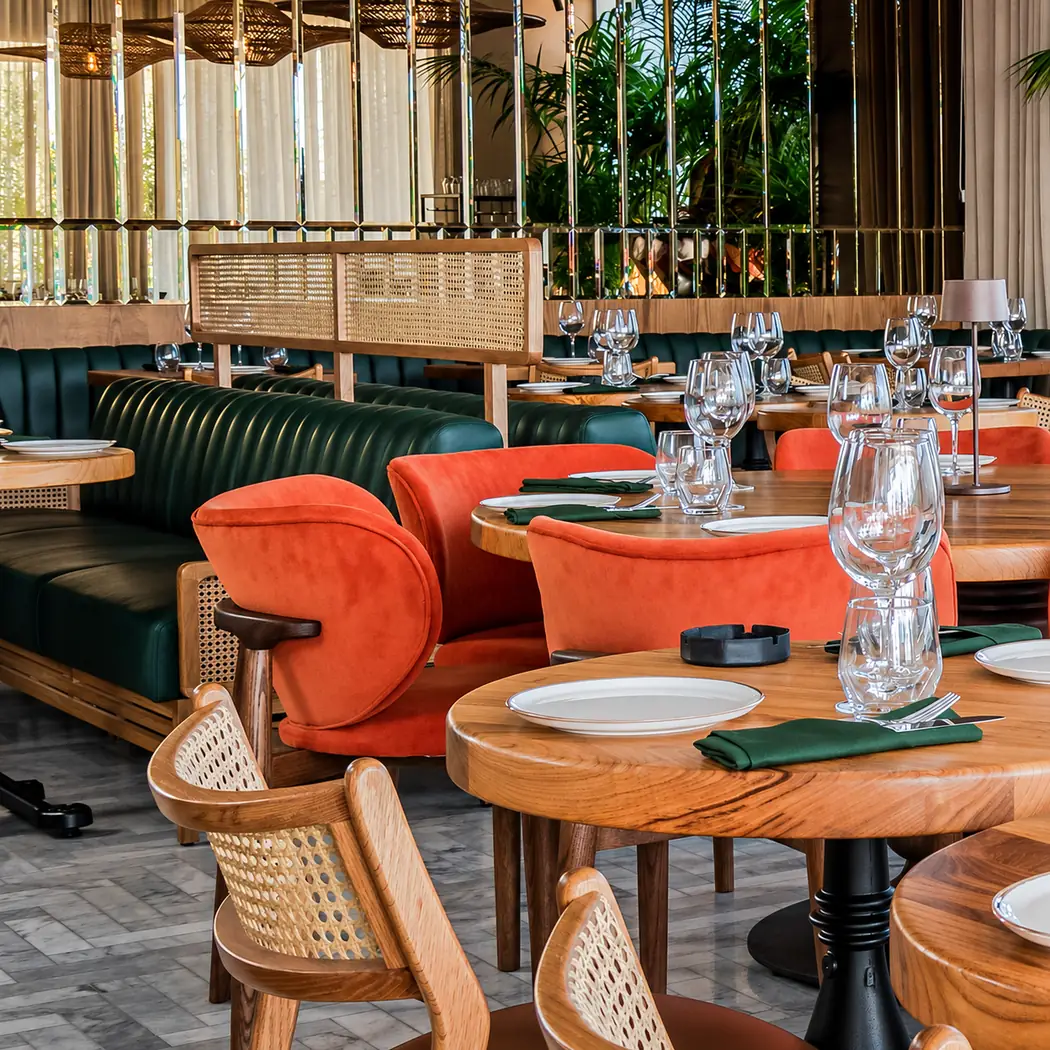 Tables en bois, banquettes vertes et fauteuils orange de la néo-brasserie Zing