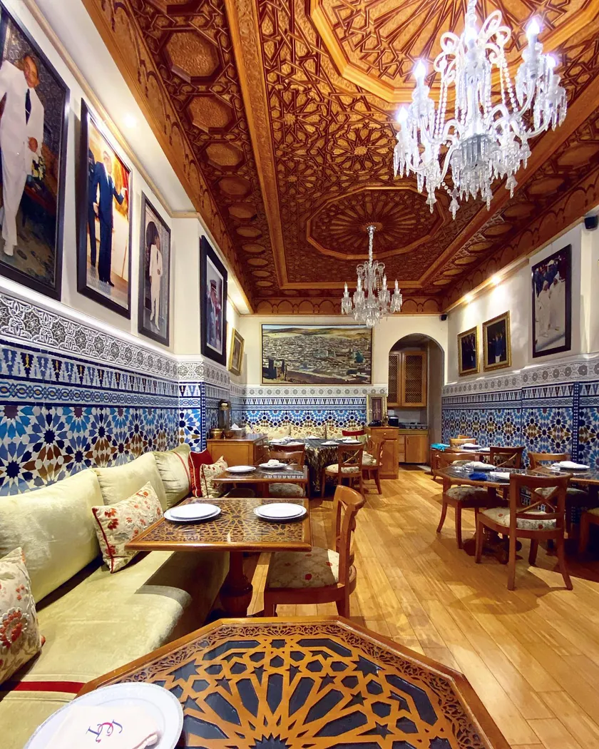 Longue salle du Cuistot Traditionnel avec banquettes, plafond sculpté et lustres