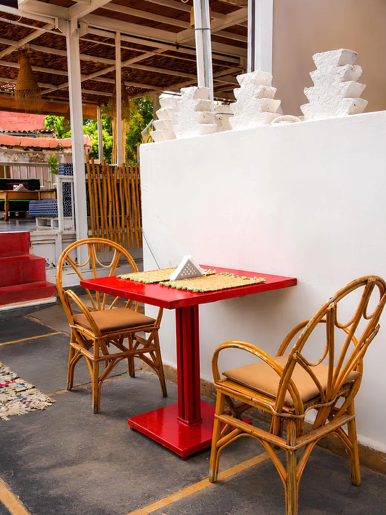 Coin de la terrasse de Kui-Zin avec table rouge et chaises en rotin