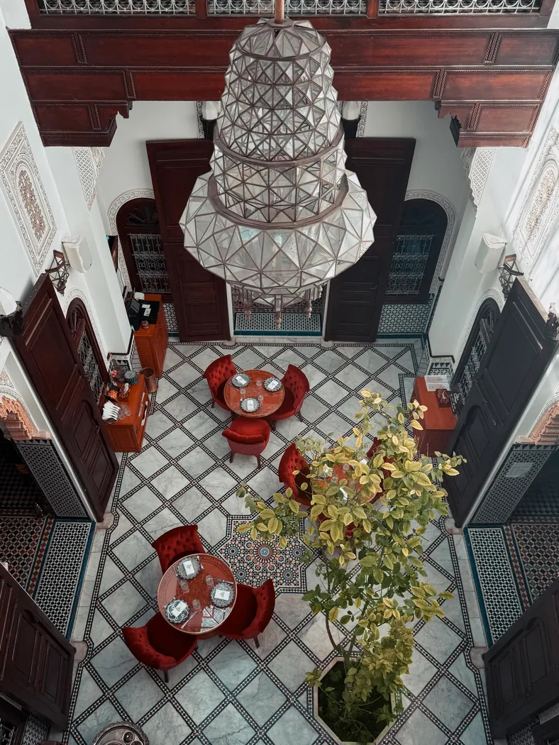 Patio de MaQam aux Habous vu d'en haut : grand lustre, sol en damier et chaises rouges