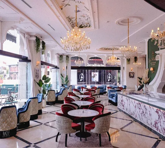 Salle de La Môme à Marrakech : lustres en cristal, comptoir en marbre et fauteuils bordeaux