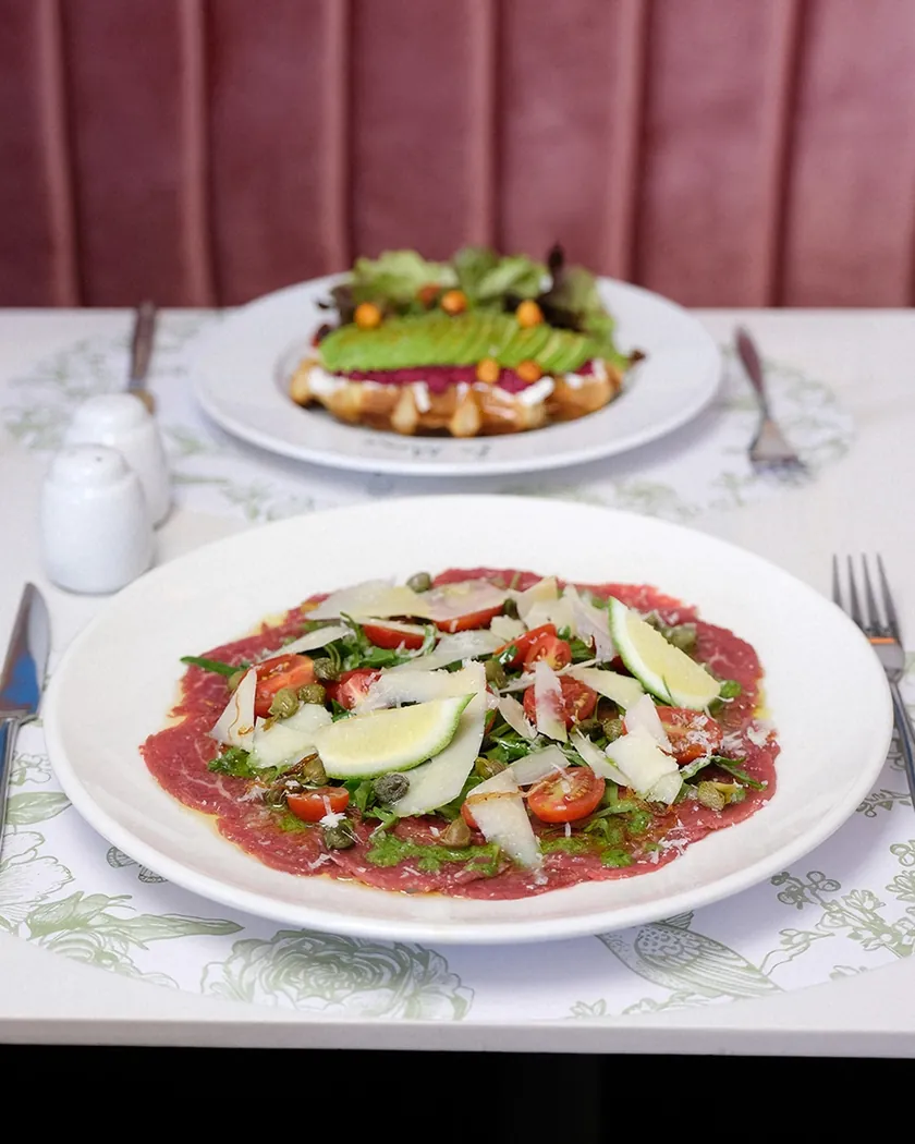 Carpaccio de bœuf et tartine à l'avocat sur une table en marbre de La Môme