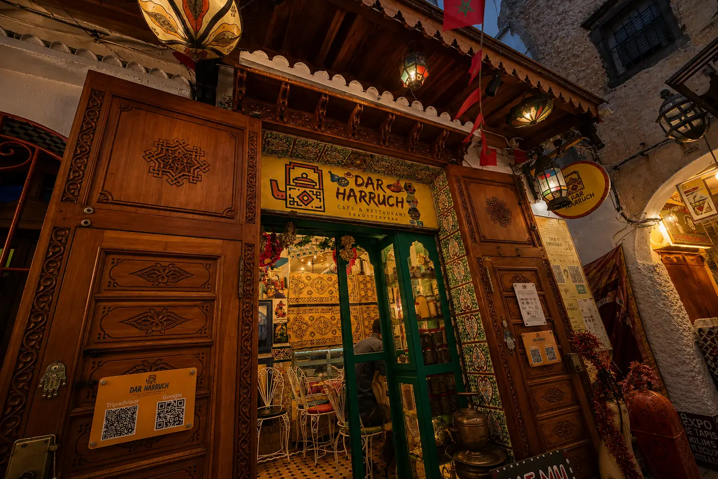Porte en bois sculpté et enseigne de Dar Harruch dans une ruelle de la médina de Tanger