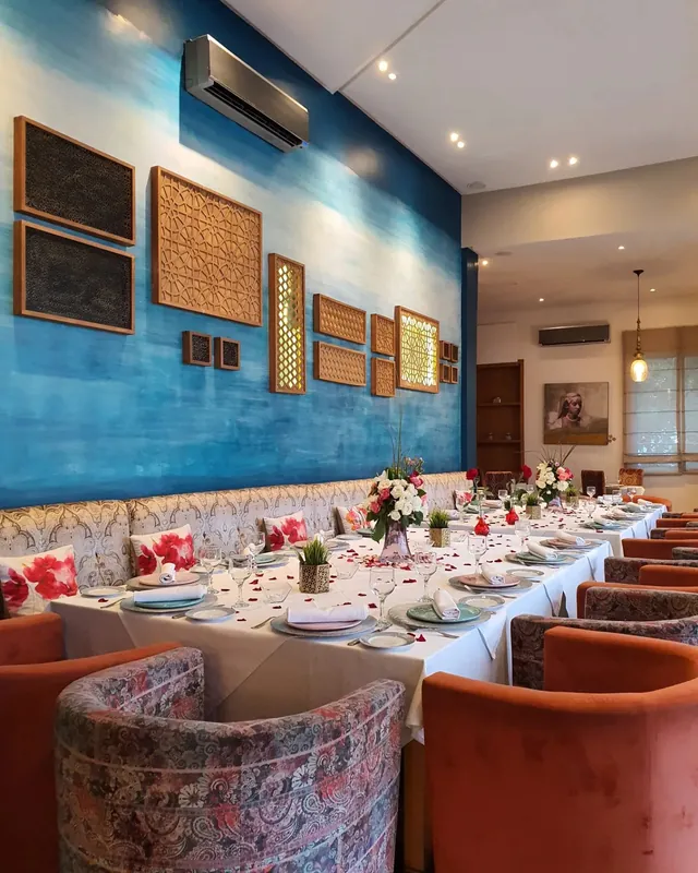 Longue table dressée pour un groupe devant un mur bleu décoré de cadres, Riad 21