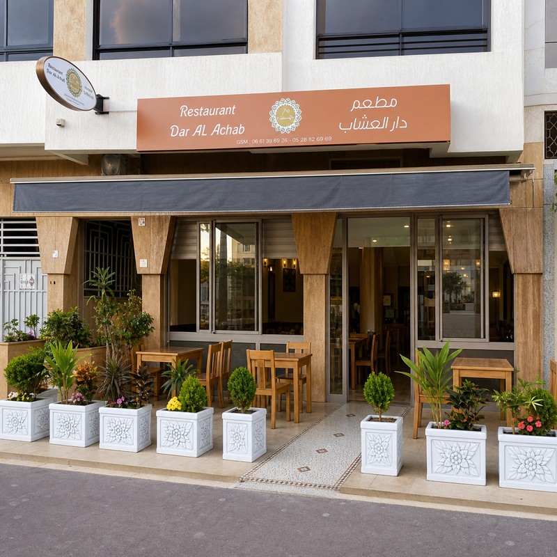 Façade de Dar Al Achab avec enseigne bilingue, auvent et jardinières blanches