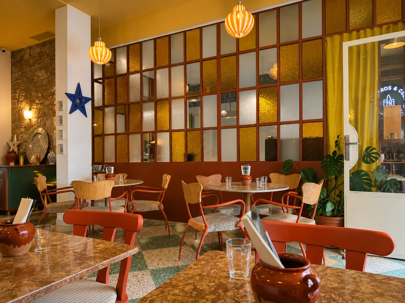 Salle lumineuse de Soli avec suspensions orange et verrière colorée