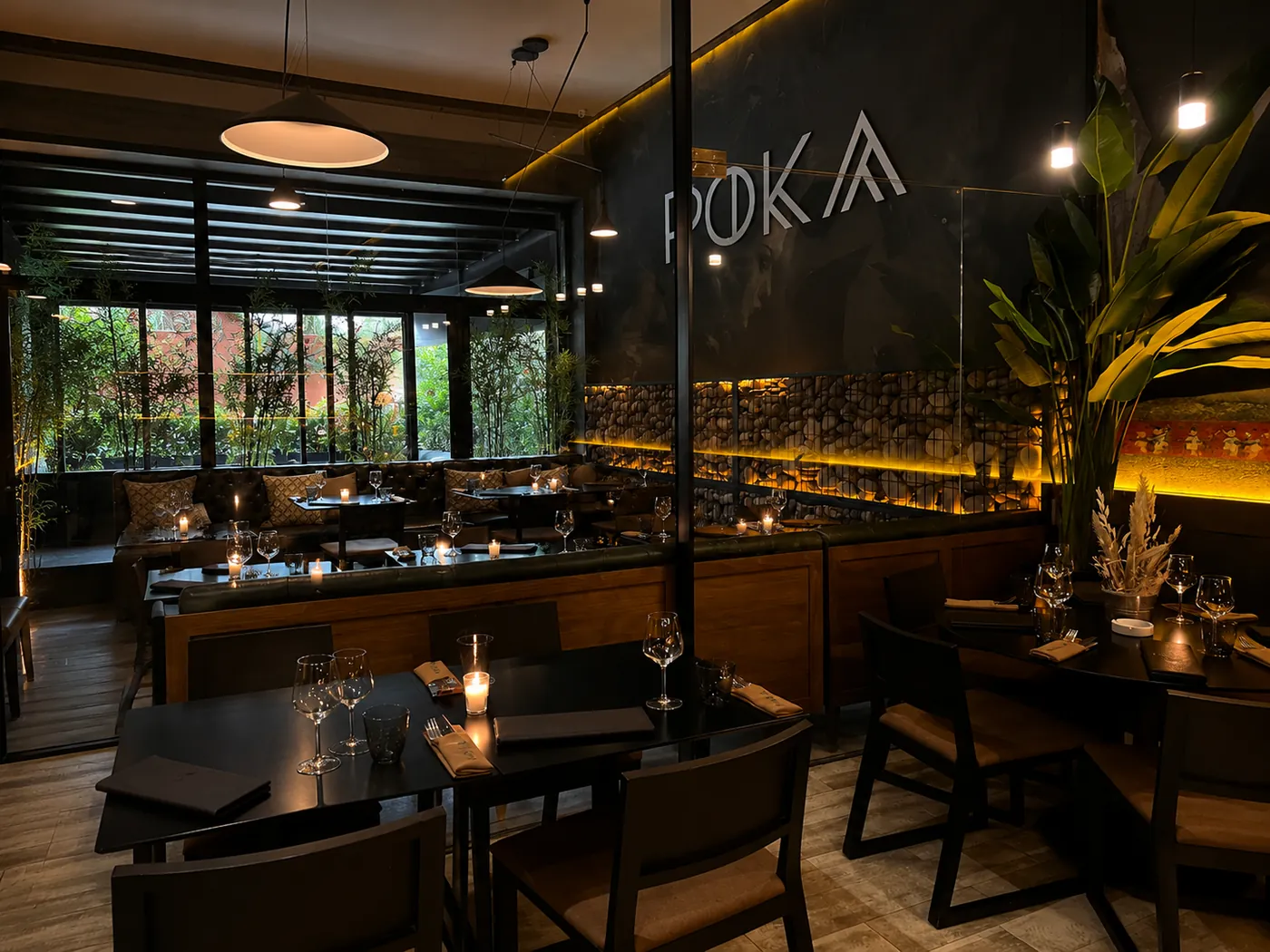Salle de Poka by Katsura à Marrakech : tables sombres, bougies, verrière végétale et logo Poka au mur