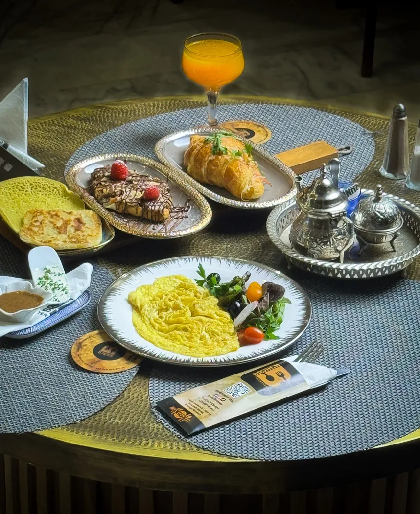 Omelette, crêpe marocaine, croissant et service à thé sur une table ronde chez Brunch Terrasses