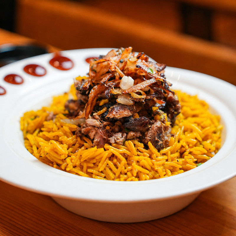 Assiette de riz épicé surmonté de shawarma et d'oignons frits chez Shawarma Al Haram