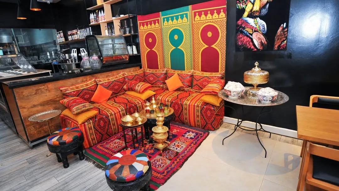Coin salon de Dar Kasri à Rabat : banquette en tissu berbère, poufs, plateau à thé et panneaux en arche