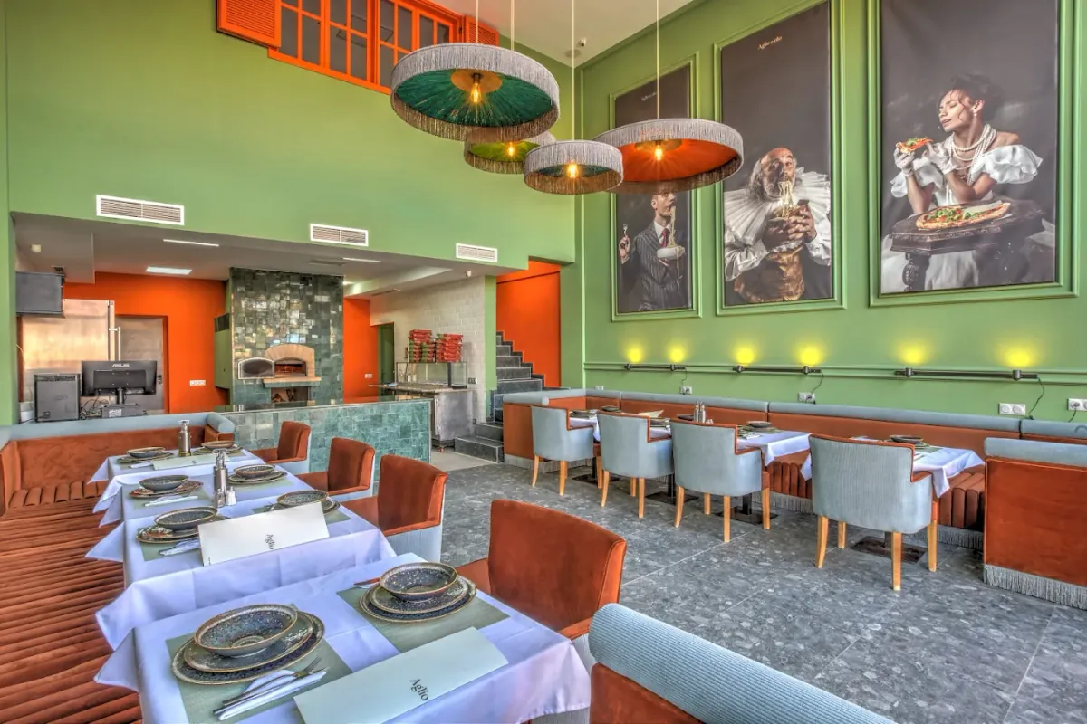 Aglio e Olio à Marrakech : grande salle aux murs verts, portraits peints et suspensions à franges