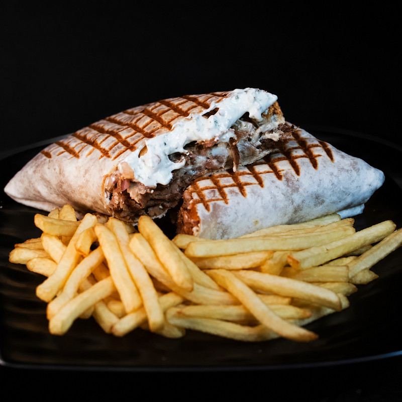 Durum grillé à la sauce blanche coupé en deux avec frites chez Quick Kebab