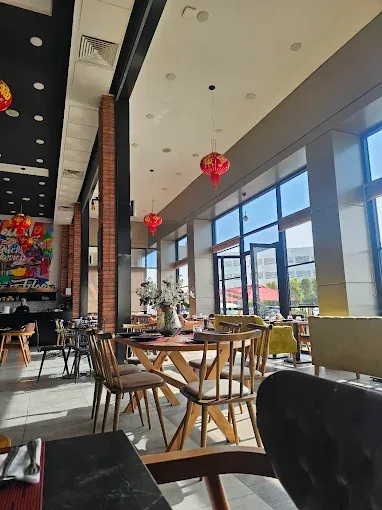 Salle d'Ô'Sushi Lounge : briques, lanternes rouges et chaises en bois face aux baies vitrées