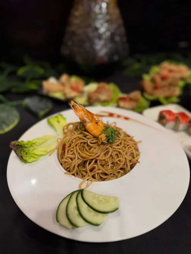 Nouilles sautées surmontées d'une crevette dans une assiette blanche chez Ô'Sushi Lounge