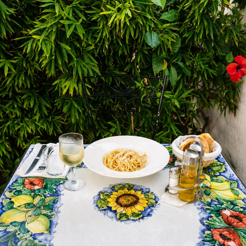 Il Giardino à Rabat : spaghetti et verre de vin sur une table en céramique sicilienne, dans le jardin