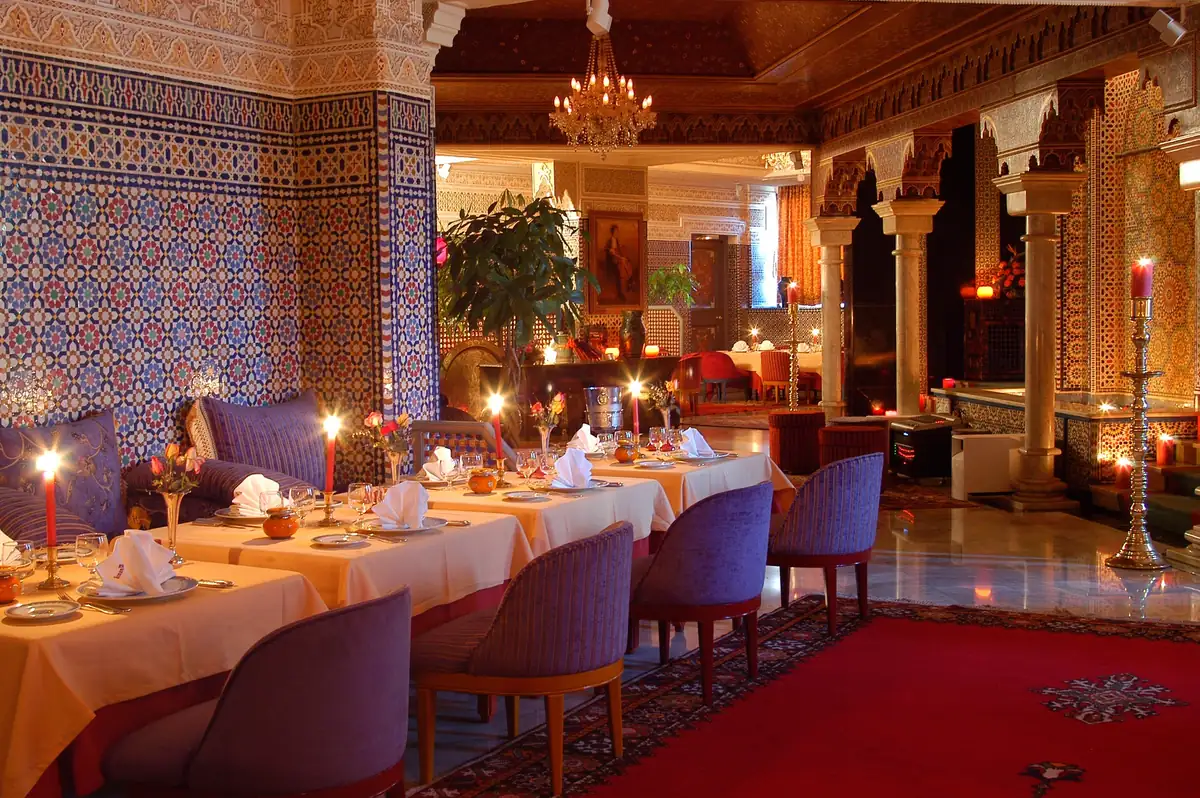 Salle du Basmane à Casablanca : murs en zellige, bougies, tapis rouge et tables nappées