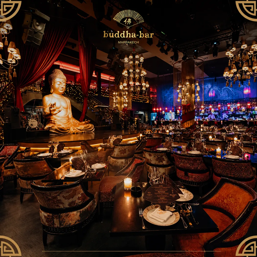 Salle du Buddha-Bar Marrakech : statue dorée de Bouddha, lustres, tables dressées et fauteuils à motifs