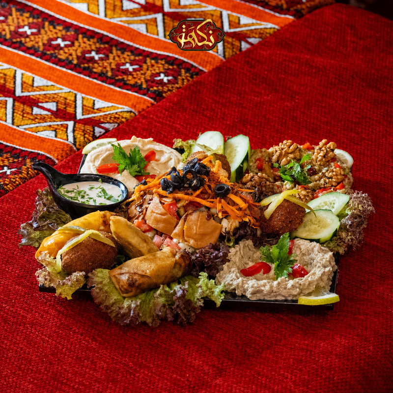 Assortiment de mezzés, falafels et feuilletés sur nappe rouge chez Nakhat Chef Nour