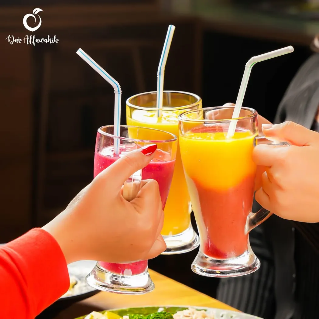 Trois verres de jus de fruits frais trinqués au-dessus d'une table chez Dar Al Fawakih