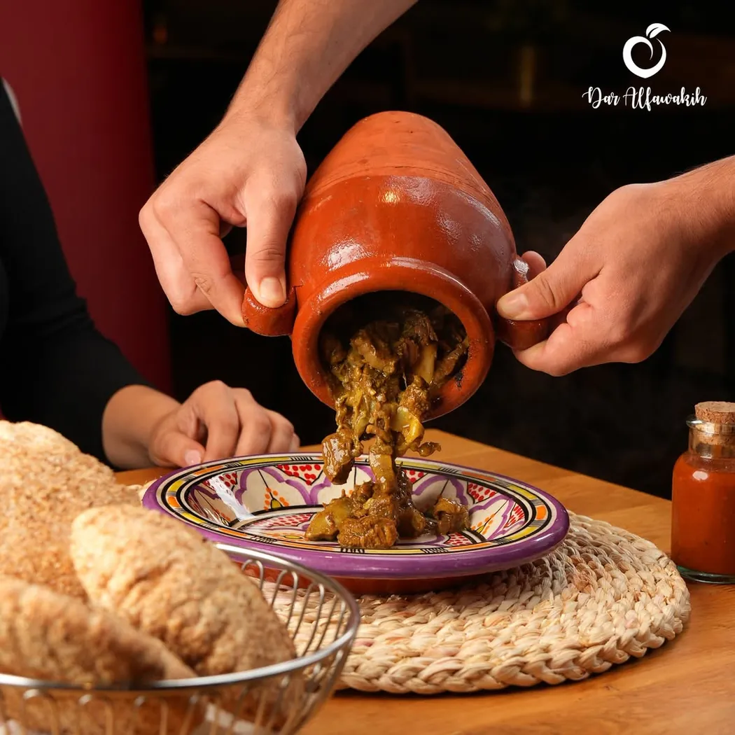 Tanjia versée de sa jarre en terre cuite dans une assiette, pain en panier à côté, chez Dar Al Fawakih