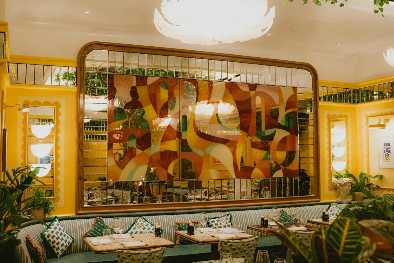 Cicchetti : salle aux murs jaunes, grande fresque encadrée d'un miroir et plantes vertes