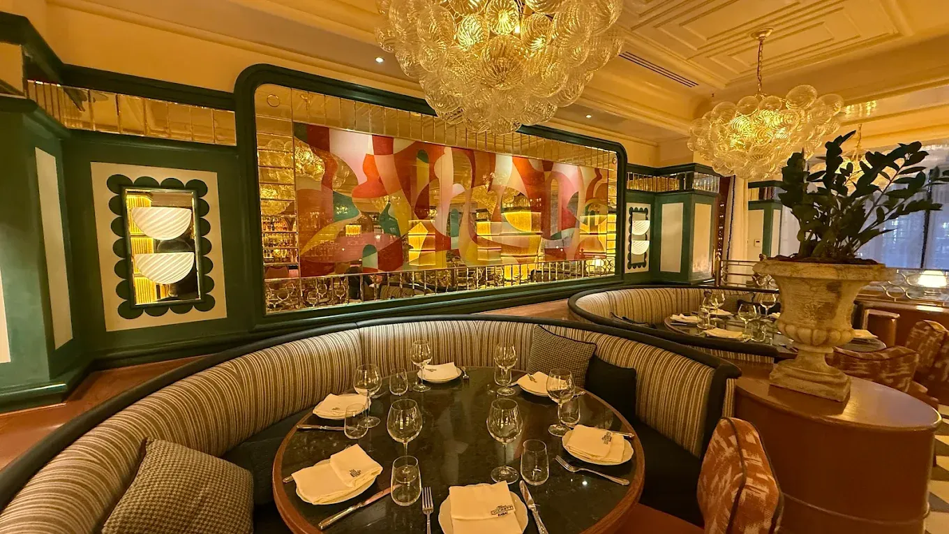 Cicchetti : banquette arrondie rayée autour d'une table dressée, fresque colorée au mur