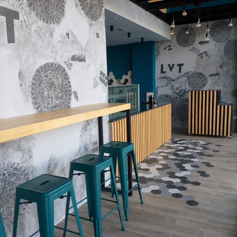 Intérieur de Le Very Table : tabourets bleus, comptoir en bois et sol en tomettes hexagonales