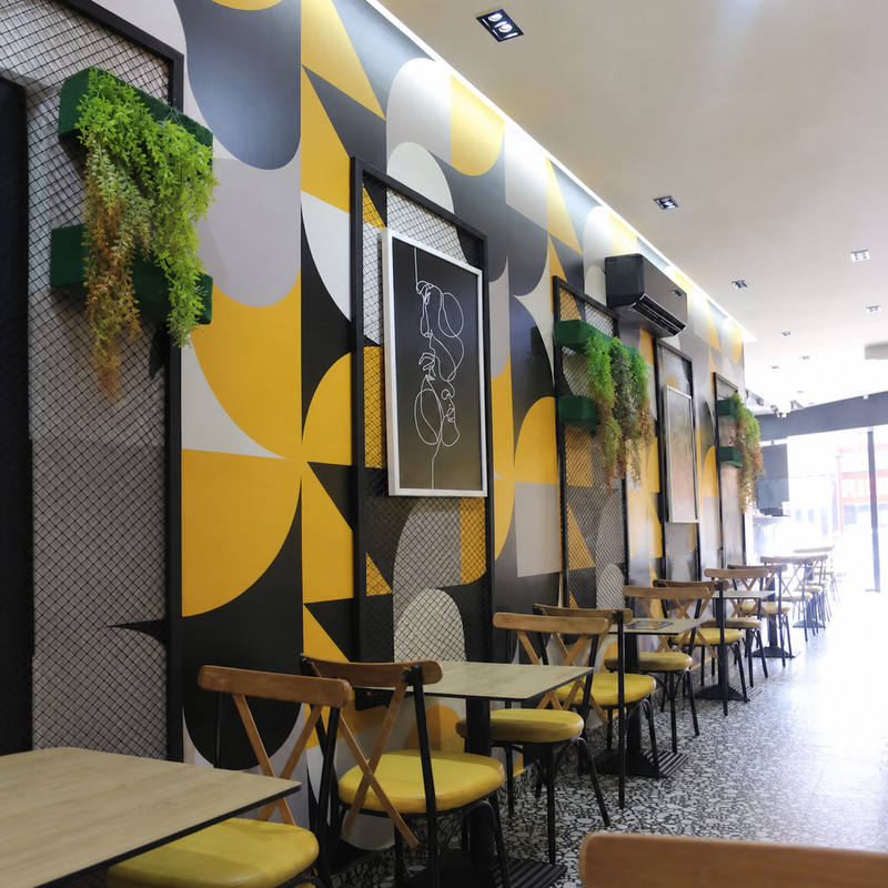 Salle de Shawarma Bros aux murs graphiques jaunes, noirs et gris, chaises jaunes