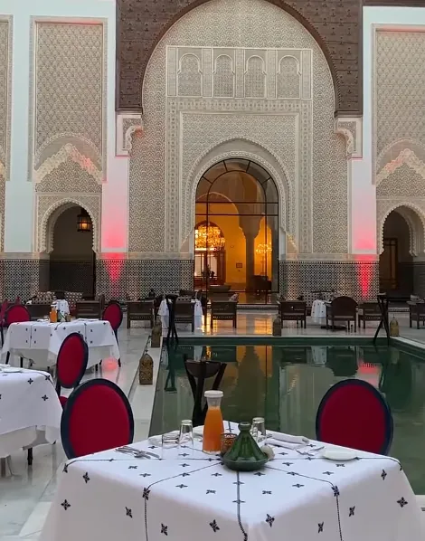 Tables dressées autour du bassin dans la cour de The Oberoi Marrakech