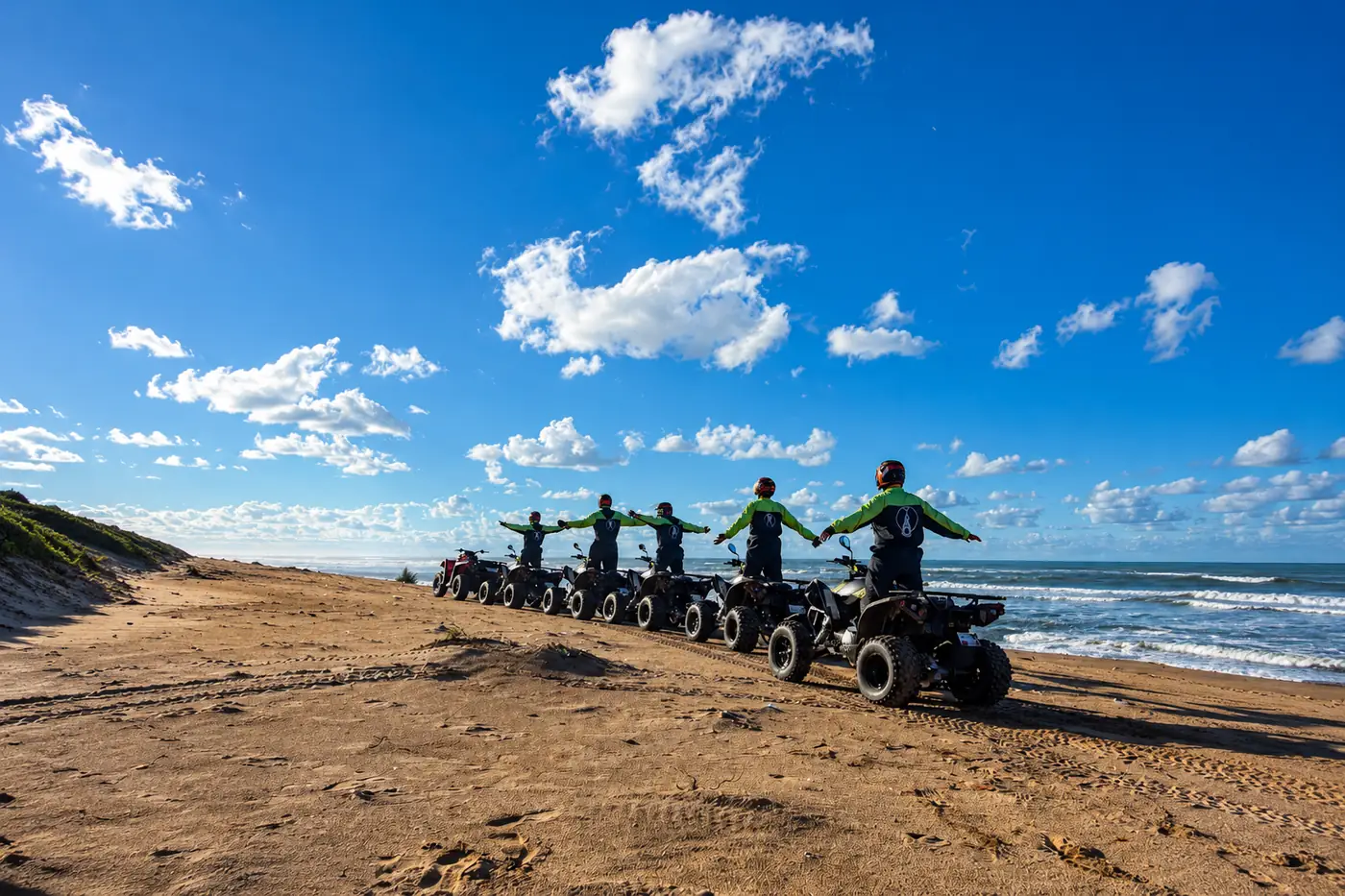 Groupe de pilotes Quad Friends debout sur leurs quads au bord de l'océan