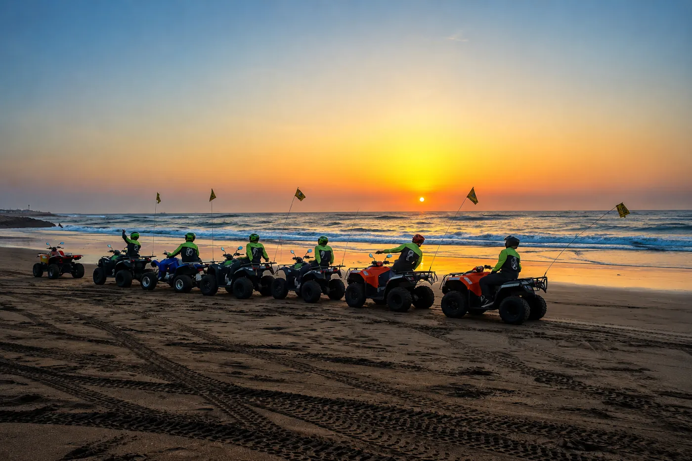File de quads Quad Friends sur la plage au coucher du soleil, face à l'océan