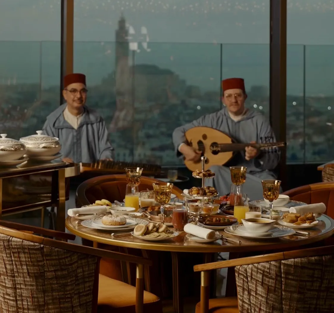 Musiciens en tenue traditionnelle, dont un joueur de oud, à une table de La Grande Table Marocaine