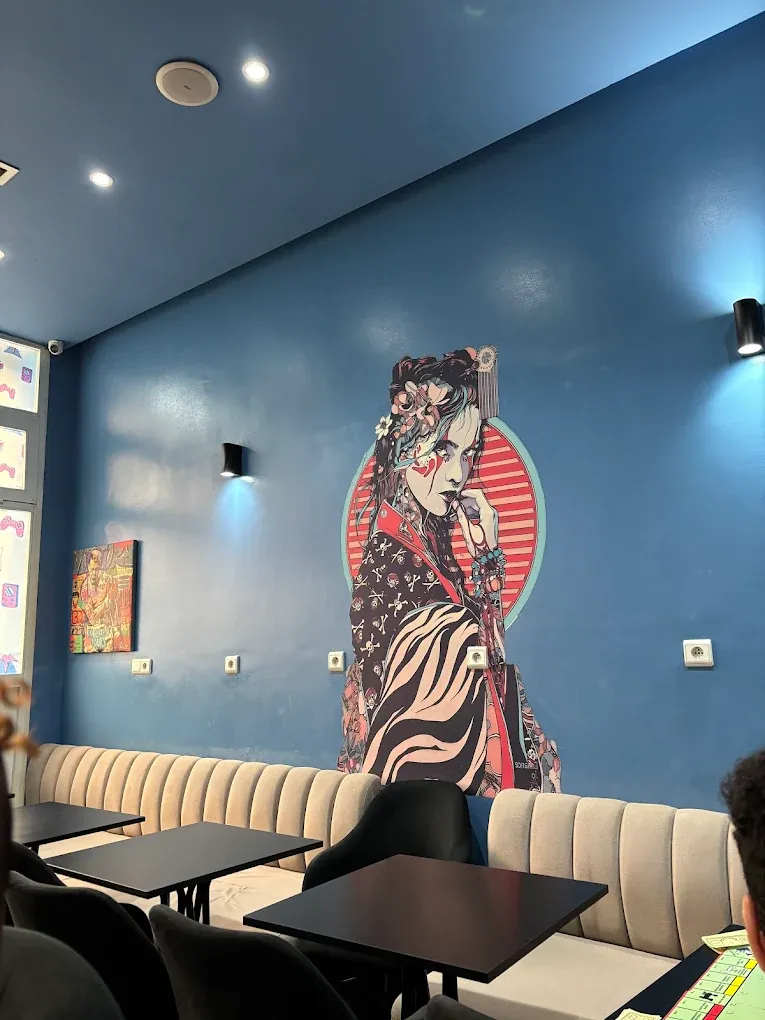 Salle de Pixel & Play : banquettes, tables noires et fresque murale