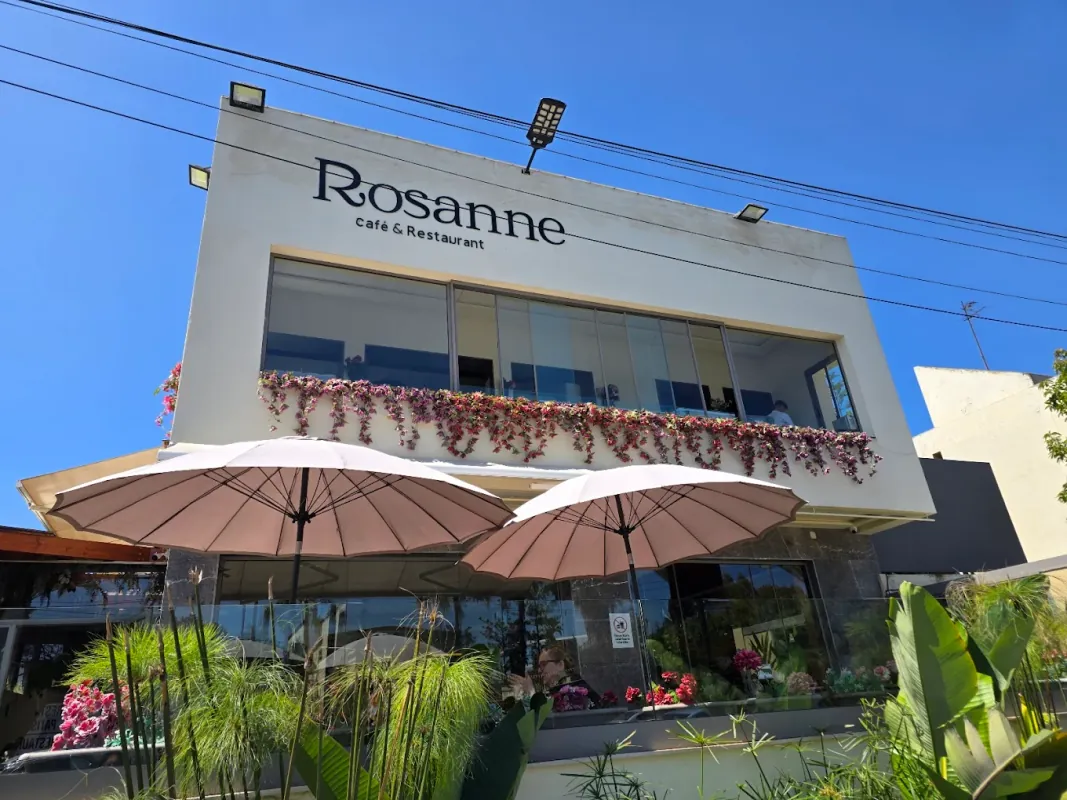 Façade de Rosanne café-restaurant, jardinières fleuries et parasols roses