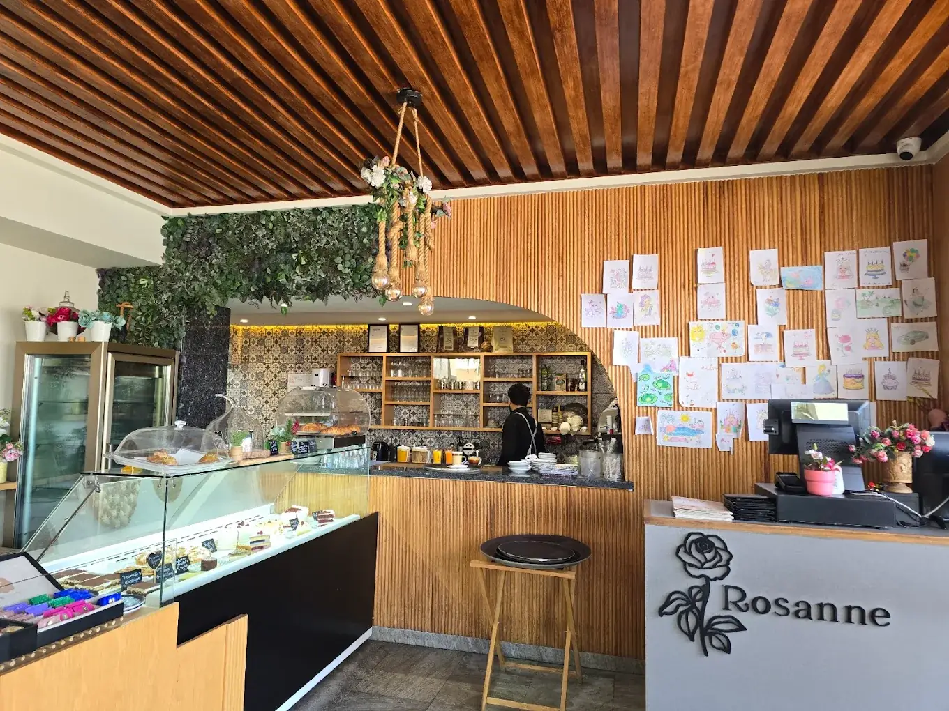 Comptoir et vitrine à gâteaux de Rosanne, dessins d'enfants au mur