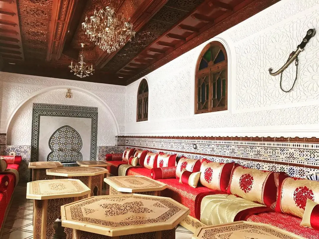 Tables octogonales en bois sculpté et banquettes brodées chez Riad Al Andalous