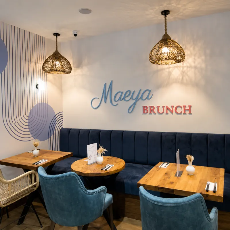 Salle de Maeya : banquette bleu nuit, tables en bois et inscription Maeya Brunch au mur
