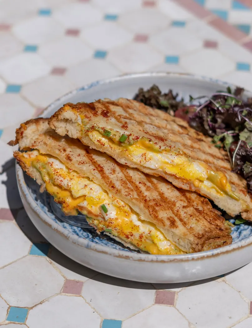 Sandwich grillé au fromage fondant et jeunes pousses servi chez Maeya