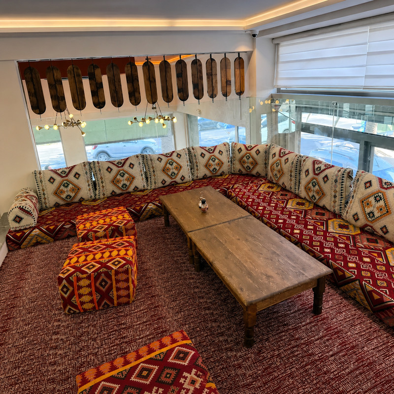 Salon oriental de Kabab Erbil avec banquettes à motifs rouges et table basse en bois